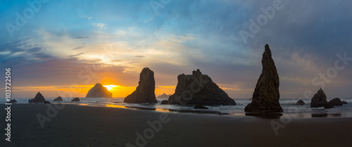 Sunset panorama at Bandon Beach over the Pacific ocean with reflections on wet sand, Bandon, Oregon