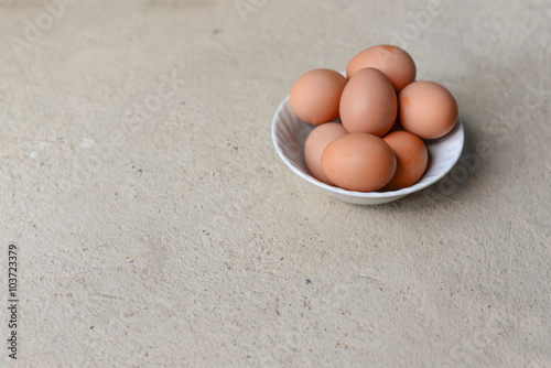 eggs in white bowl on cement floor with copy space