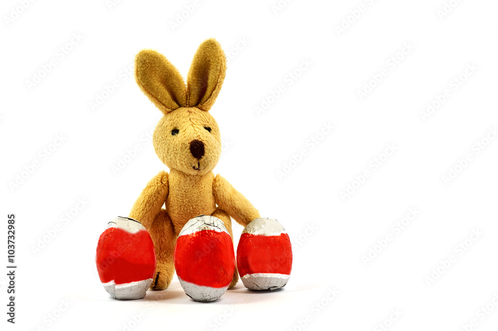 Obraz premium Easter bunny behind three eggs in a white background