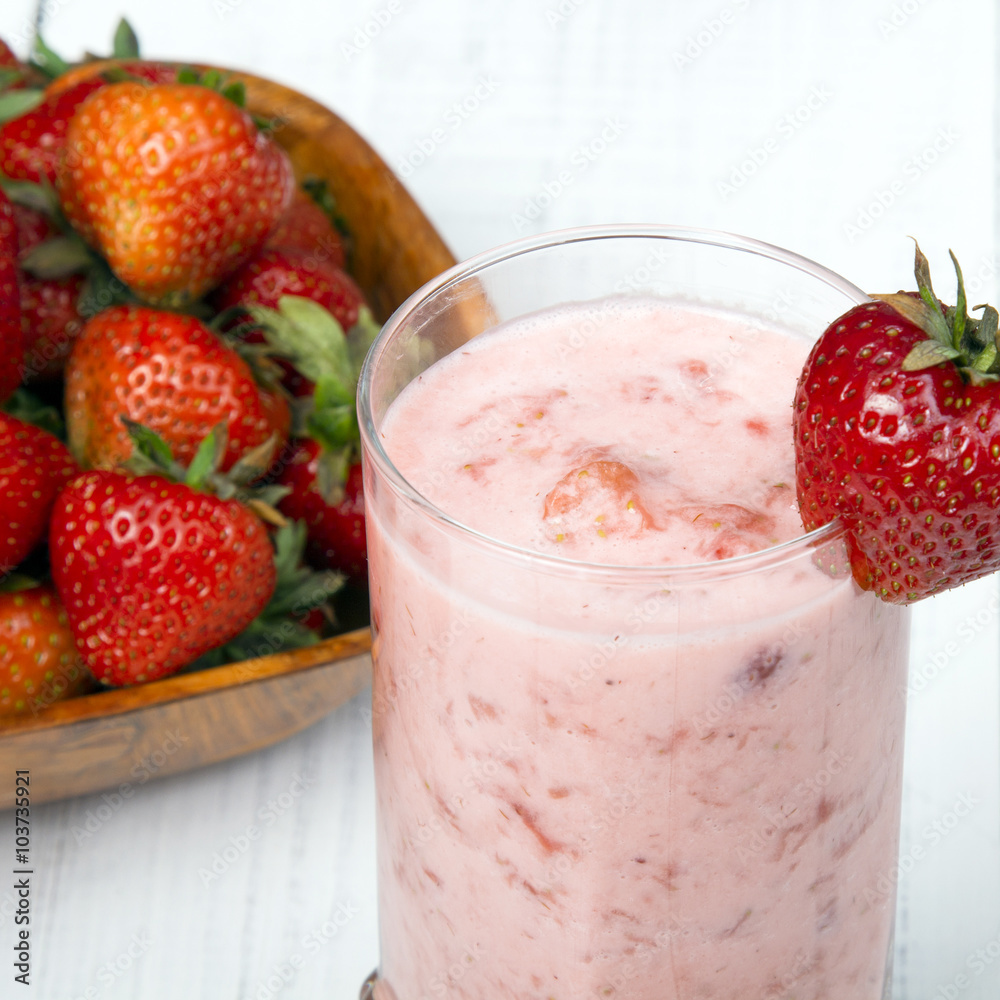 Fresh organic strawberries in bowl on white wooden background