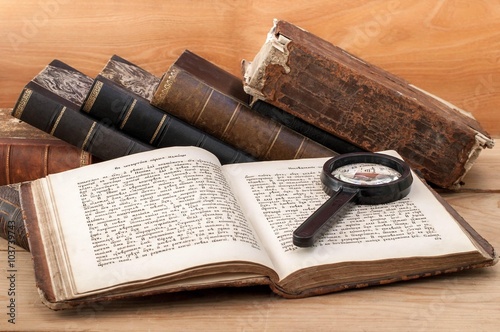 Antiquarian open book and magnifying glass on the table