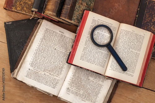 Antiquarian open book and magnifying glass on the table