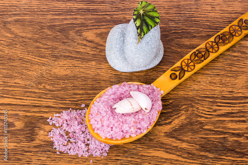 Sea salt, leaf plants, wooden spoon and two stones lying on wood