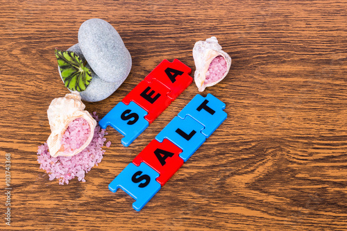 Sea salt , lettering, sheet plants, and two stones lying on wood