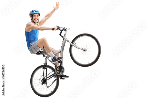 Confident young biker performing a wheelie