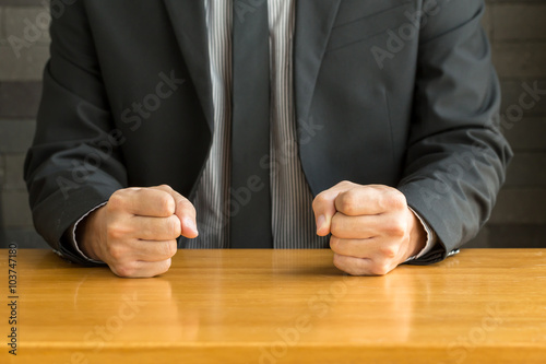 Businessman with clenched fist on the desk at office