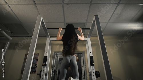 Sweaty slender girl pulls on crossbar