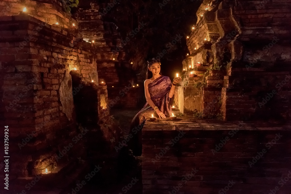 Beautiful Thai girl in Thai traditional costume with candle at night