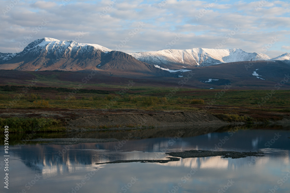 Reflection of snow-covered mountains in a tranquil river. Polar Urals. Russia.