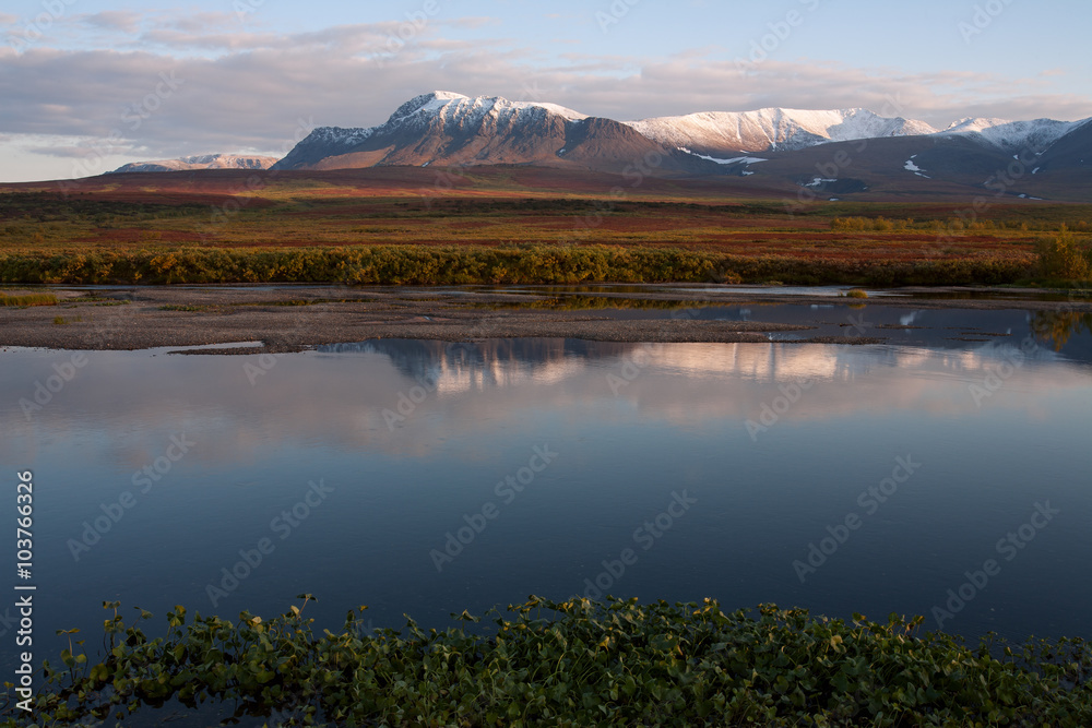 Fototapeta Reflection of snow-covered mountains in a tranquil river. Polar Urals. Russia.