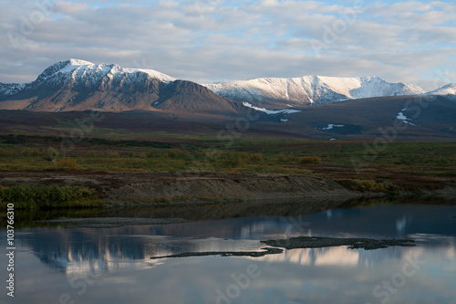 Reflection of snow-covered mountains in a tranquil river. Polar Urals. Russia.