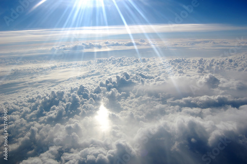 Clouds, sun, sky as seen through window of an aircraft