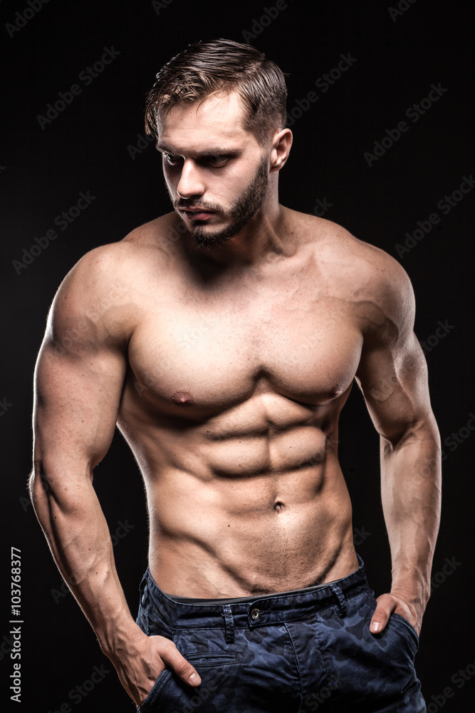 attractive bodybuilder sportsman shows perfect body muscles on black background