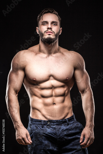 attractive bodybuilder sportsman shows perfect body muscles on black background