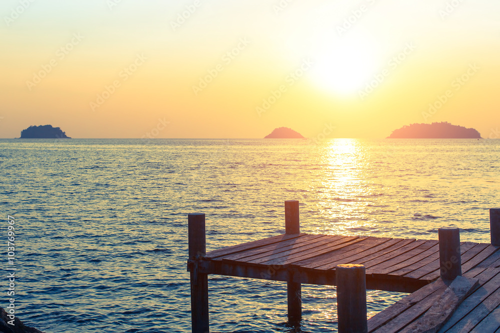 Wooden walkway on the sea coast during sunset.