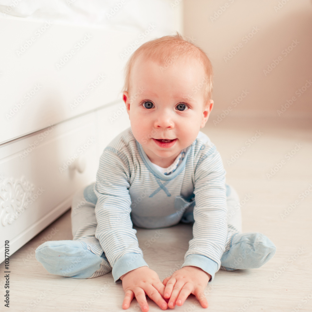 Smiling baby boy sitting on floor in room. Looking at camera. Childhood. Smiling baby boy sitting on floor in room. Looking at camera. Childhood.