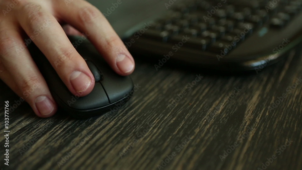 Hand of a man working at computer clicking on mouse on dark desktop Hand of a man working at computer clicking on mouse on dark desktop