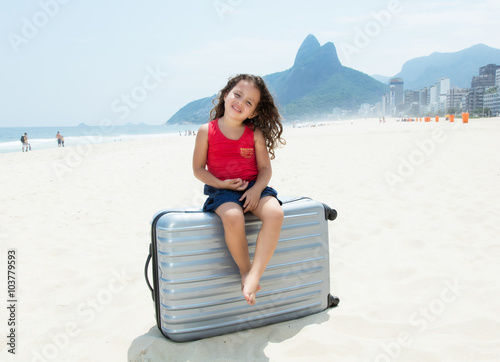 Kleines Kind mit Koffer am Strand von Rio