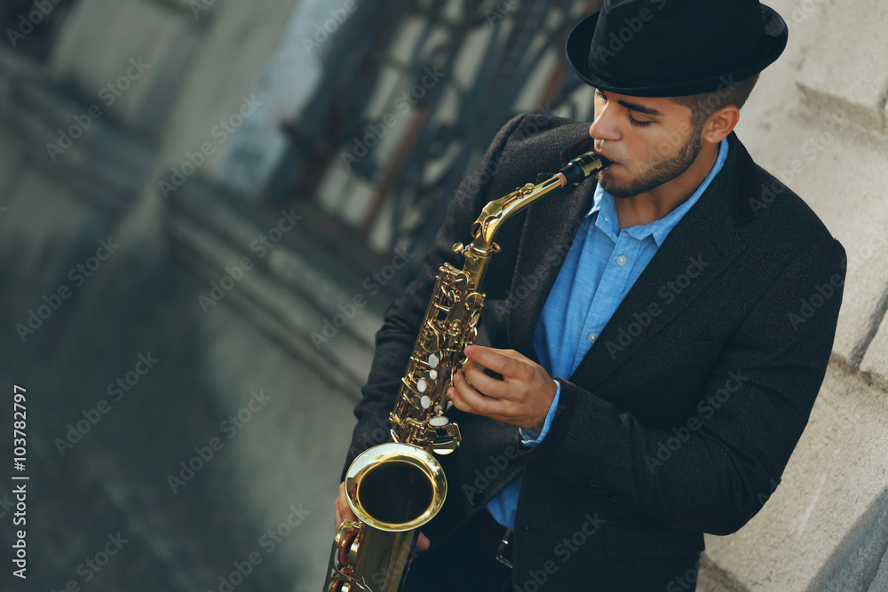 Naklejka premium Man with saxophone outside near the brick wall