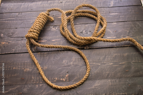 Loop hempen ropeon on a dark wood tables background. Running knot.