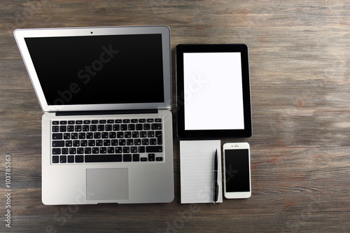 Modern laptop, tablet, mobile phone and notebook on the table