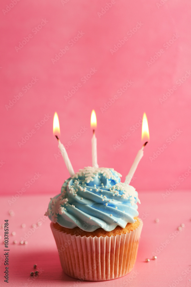 Tasty cupcake decorated with candle on pink background Tasty cupcake decorated with candle on pink background