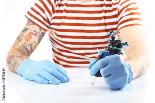 Tattoo master working in blue medical gloves with tattoo machine  close up