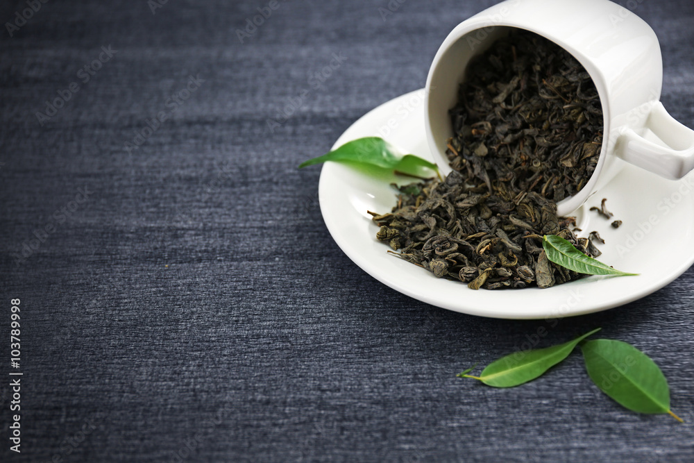 Granulated tea with green leaves in tea-set on grey background Granulated tea with green leaves in tea-set on grey background
