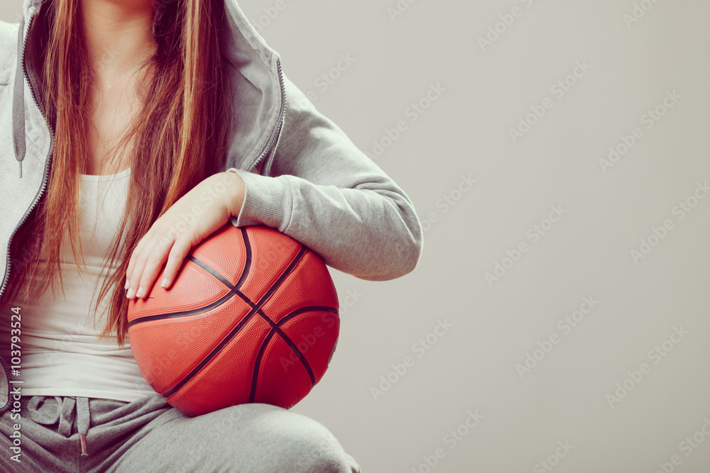 Obraz premium Sporty teen girl in hood holding basketball.