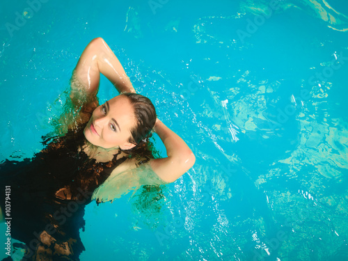 Woman floating relaxing in swimming pool water.