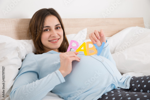 Pregnant Woman With Text Baby Lying On Bed