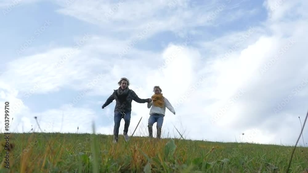 Young couple running down the hill laughing and holding hands Young couple running down the hill laughing and holding hands