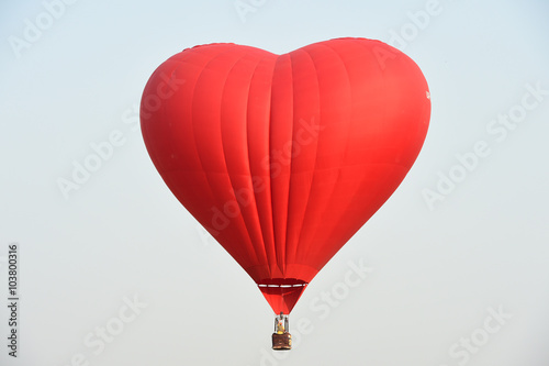 Red balloon in the shape of a heart against the blue sky
