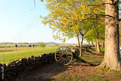 Color DSLR stock image of a row of civil war cannons and a stone wall in a field at Gettysburg, Pennsylvania battle memorial. Horizontal with copy space for text photo