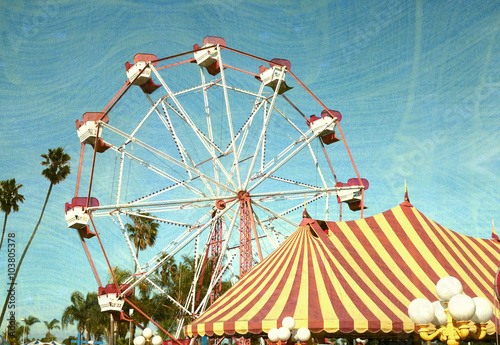 aged and worn vintage photo of ferris wheel with palm trees