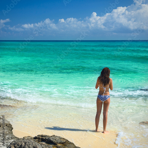 Obraz na płótnie Young fashion woman in bikini looking on sea at tropical beach. w salonie
