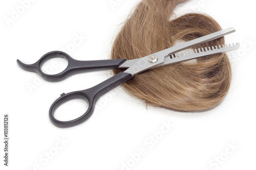 Hairdressers scissors against the backdrop of strand of female h