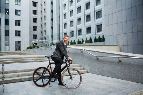 businessman with the bike going up the stairs on the background of business centers