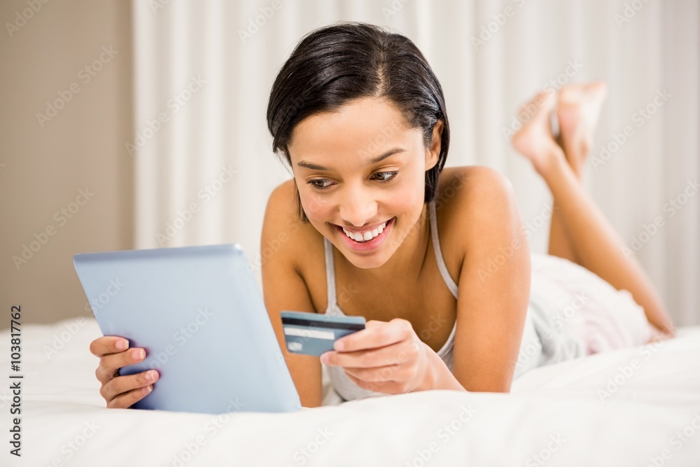 Smiling brunette using tablet and holding credit card Smiling brunette using tablet and holding credit card