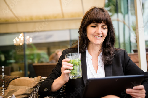 Senior business woman drinking mojito and working