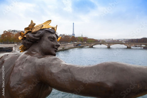 Sculpture in the Alexandre III bridge and Eiffel tower in Paris, France