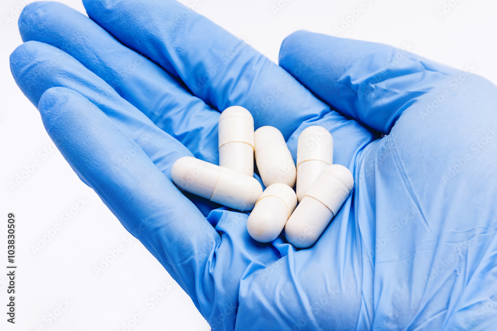Fototapeta premium Hand in blue glove holding pills.