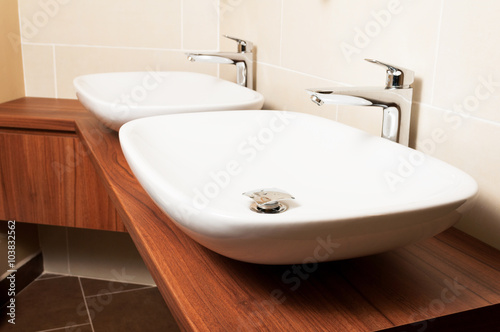 White ceramics sinks and chromed taps in washroom