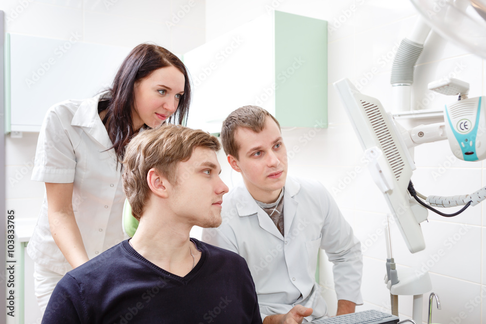 Fototapeta premium Young man patient at dentist office with doctor and assistant