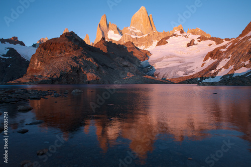 The top of Fitz Roy in pink sunrise and reflections in the lake. Patagonia. Argentina.