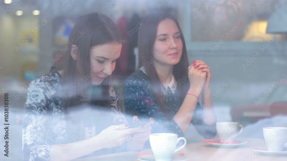 Beautiful girl showing a smartphone girlfriend in cafe Beautiful girl showing a smartphone girlfriend in cafe