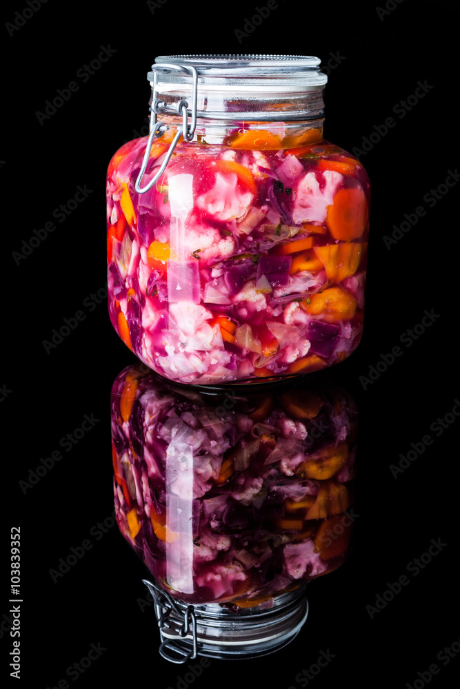 Big glass jar with colourful pickled vegetables on black background with reflection vertical Big glass jar with colourful pickled vegetables on black background with reflection vertical