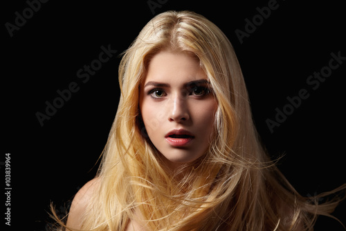 Portrait of blonde girl with flying hair on black background