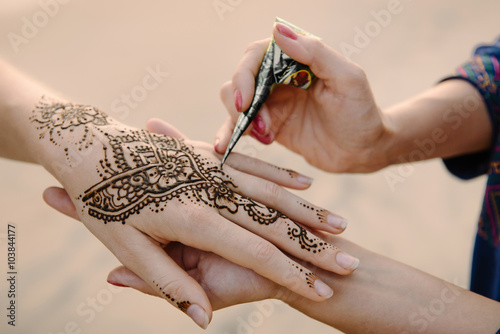 applying henna tattoo on women hands photo
