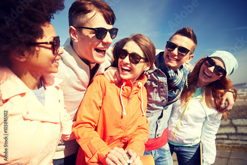 smiling friends in sunglasses laughing on street